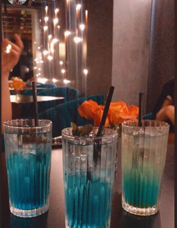 Three blue cocktails with orange flowers