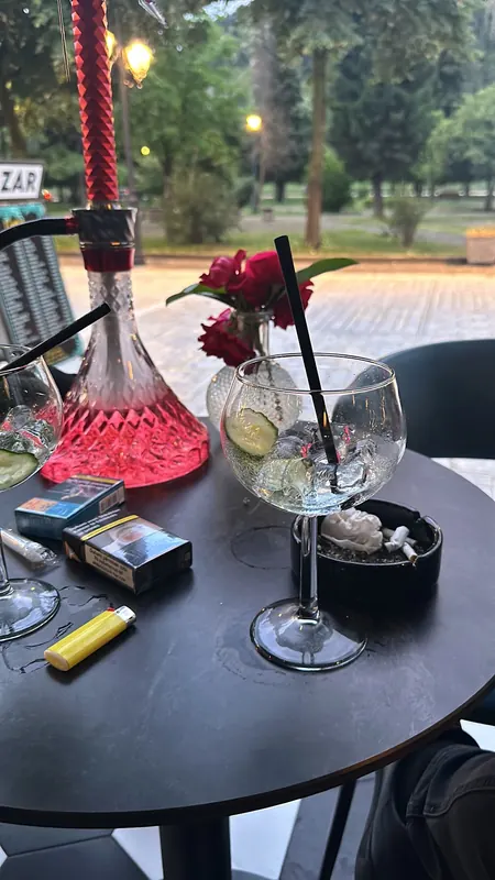 A shisha and a gin glass on a terrace table, with the park behind